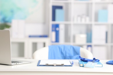 Photo of Doctor's workplace with stethoscope, paperwork and laptop on desk. Space for text