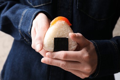Photo of Woman with tasty onigiri (Japanese rice ball) indoors, closeup