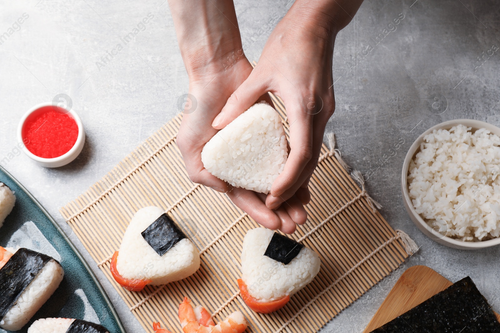 Woman making onigiri (Japanese rice balls) at light table, top view Photo of Woman making onigiri (Japanese rice balls) at light table, top view