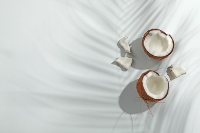 Photo of Fresh coconut and shadow cast by tropical palm on light background, flat lay. Space for text