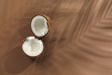 Photo of Fresh coconut and shadow cast by tropical palm on beige background, top view. Space for text