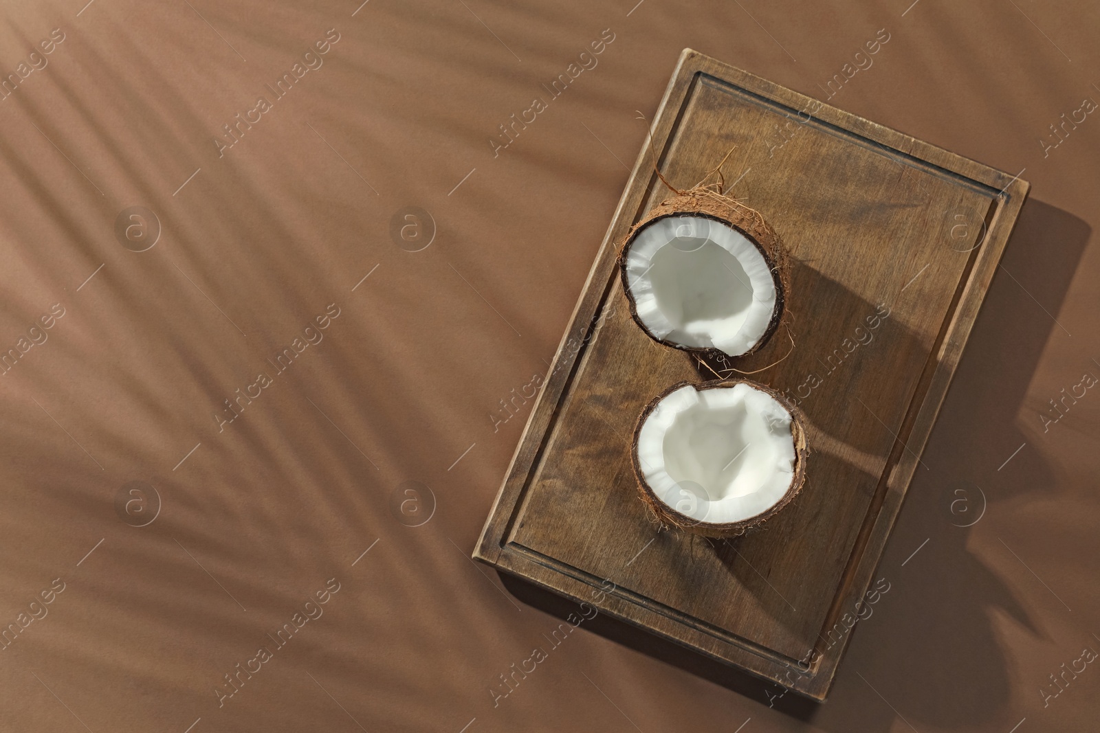 Fresh coconut and shadow cast by tropical palm on beige background, top view. Space for text Photo of Fresh coconut and shadow cast by tropical palm on beige background, top view. Space for text