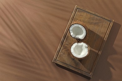 Photo of Fresh coconut and shadow cast by tropical palm on beige background, top view. Space for text