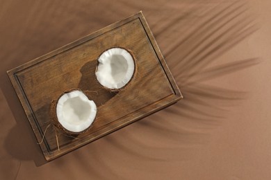 Photo of Fresh coconut and shadow cast by tropical palm on beige background, top view. Space for text