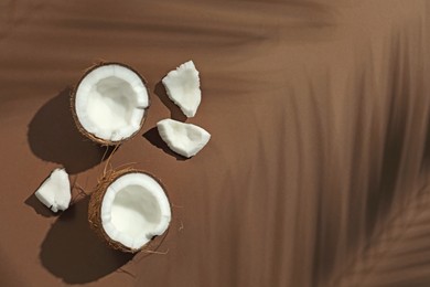 Photo of Fresh coconut and shadow cast by tropical palm on beige background, flat lay. Space for text