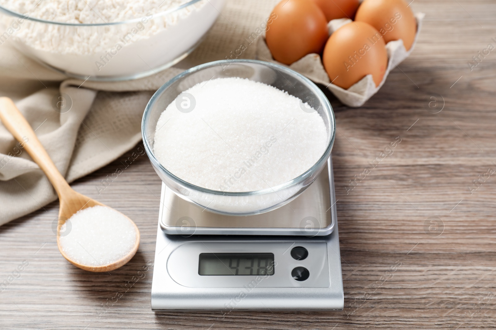 Digital kitchen scale with bowl of sugar and spoon on wooden table, closeup Photo of Digital kitchen scale with bowl of sugar and spoon on wooden table, closeup