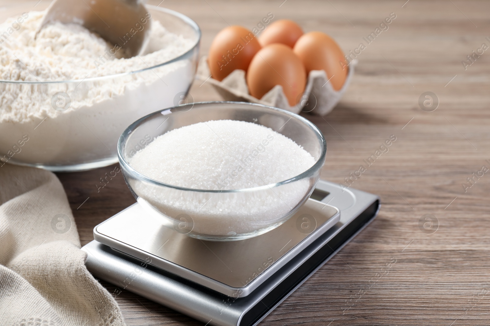 Digital kitchen scale with bowl of sugar and other products on wooden table, closeup Photo of Digital kitchen scale with bowl of sugar and other products on wooden table, closeup