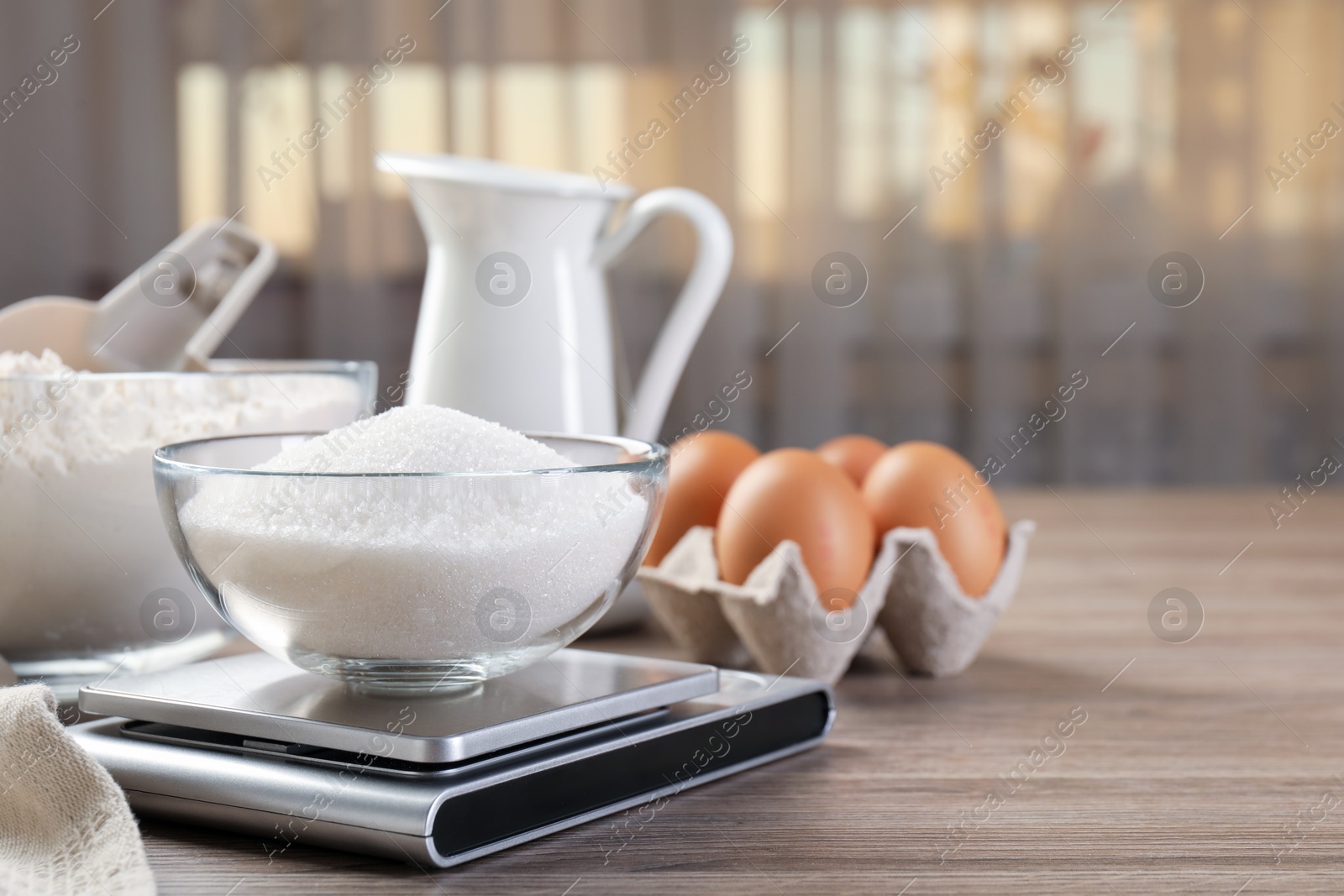 Digital kitchen scale with bowl of sugar and other products on wooden table indoors, closeup. Space for text Photo of Digital kitchen scale with bowl of sugar and other products on wooden table indoors, closeup. Space for text