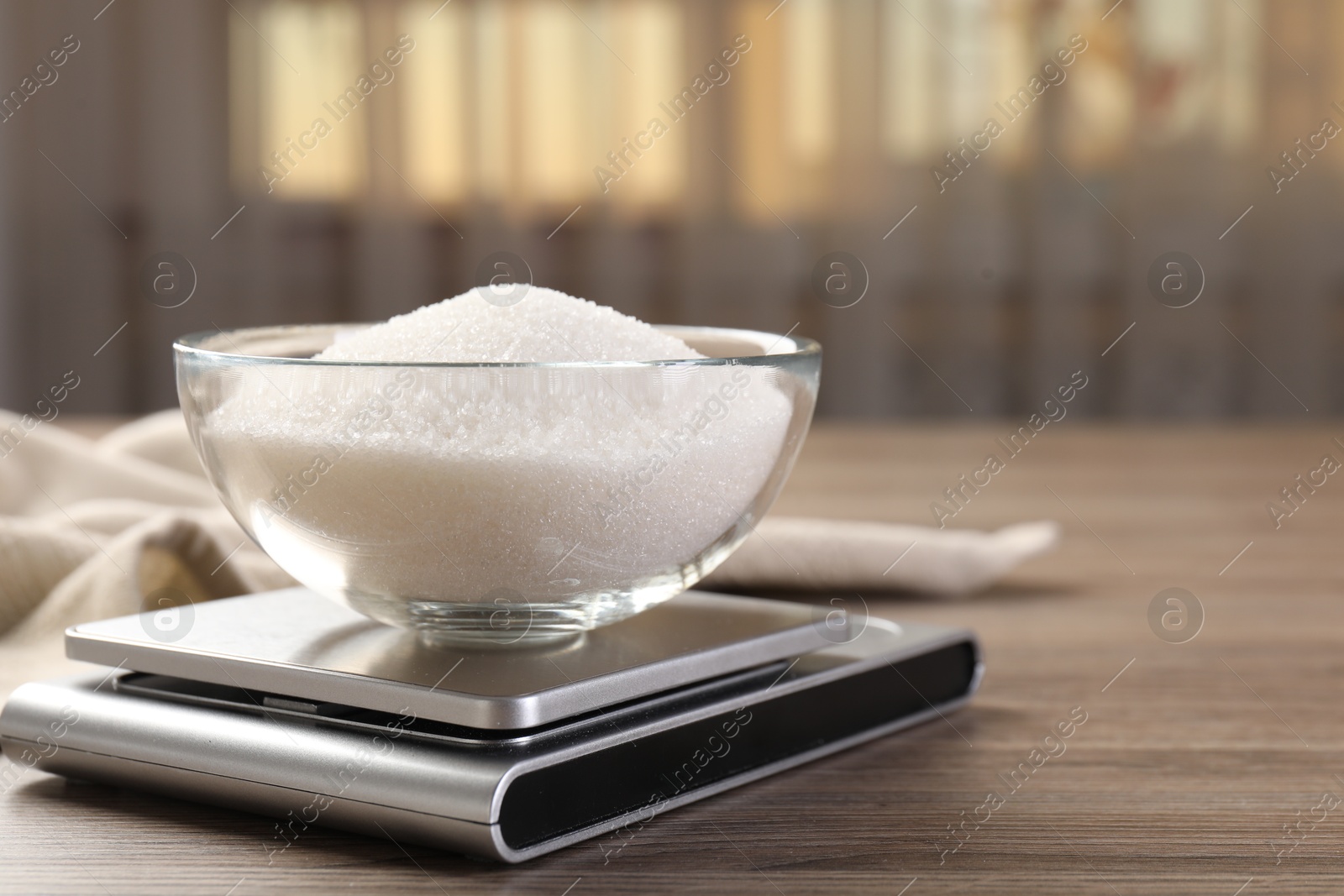 Digital kitchen scale with bowl of sugar on wooden table indoors, closeup. Space for text Photo of Digital kitchen scale with bowl of sugar on wooden table indoors, closeup. Space for text