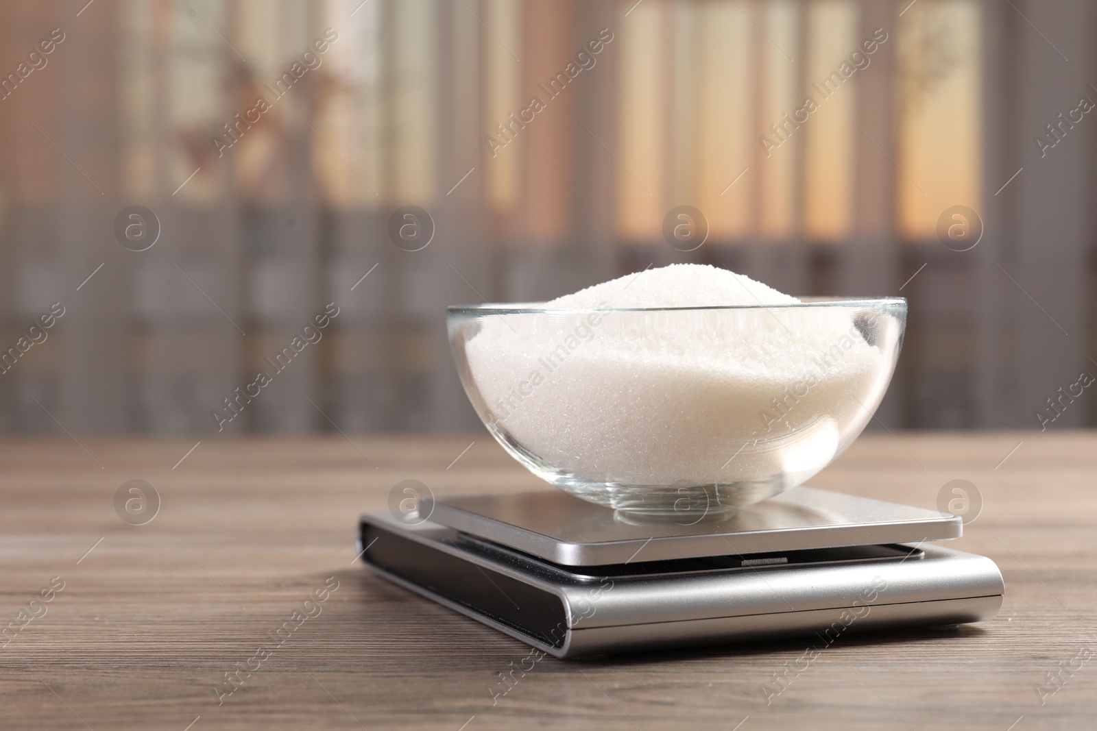 Digital kitchen scale with bowl of sugar on wooden table indoors, closeup. Space for text Photo of Digital kitchen scale with bowl of sugar on wooden table indoors, closeup. Space for text