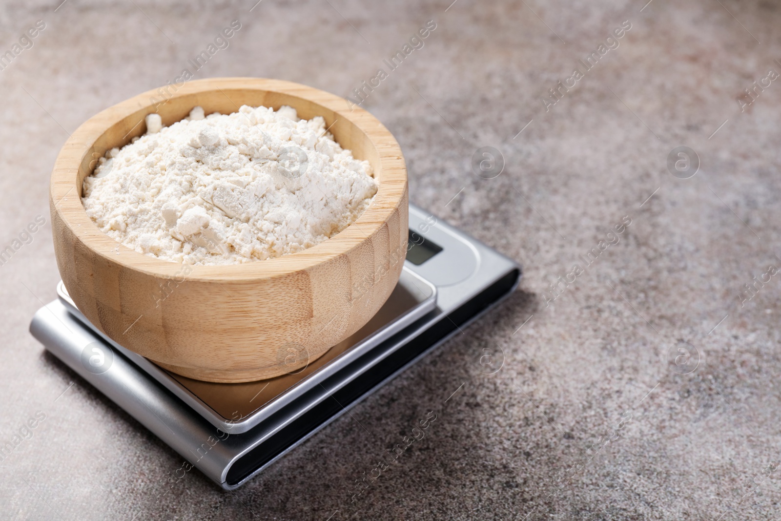 Digital kitchen scale with bowl of flour on grey textured table, closeup Photo of Digital kitchen scale with bowl of flour on grey textured table, closeup