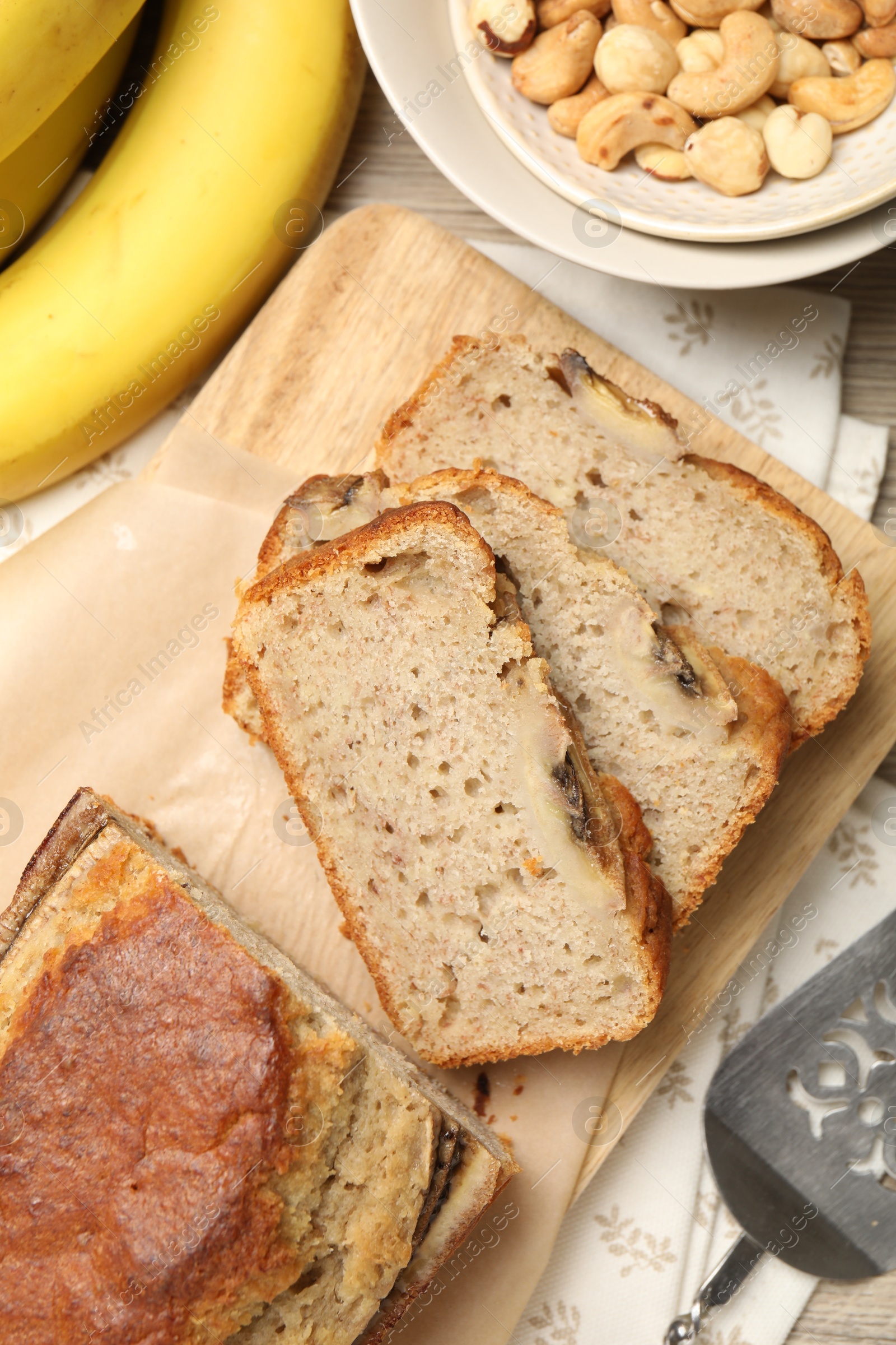 Cut banana bread with nuts, fruits and server on table, flat lay Photo of Cut banana bread with nuts, fruits and server on table, flat lay