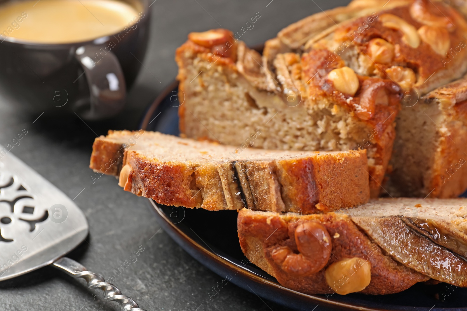 Cut banana bread with nuts, server and coffee on black table, closeup Photo of Cut banana bread with nuts, server and coffee on black table, closeup