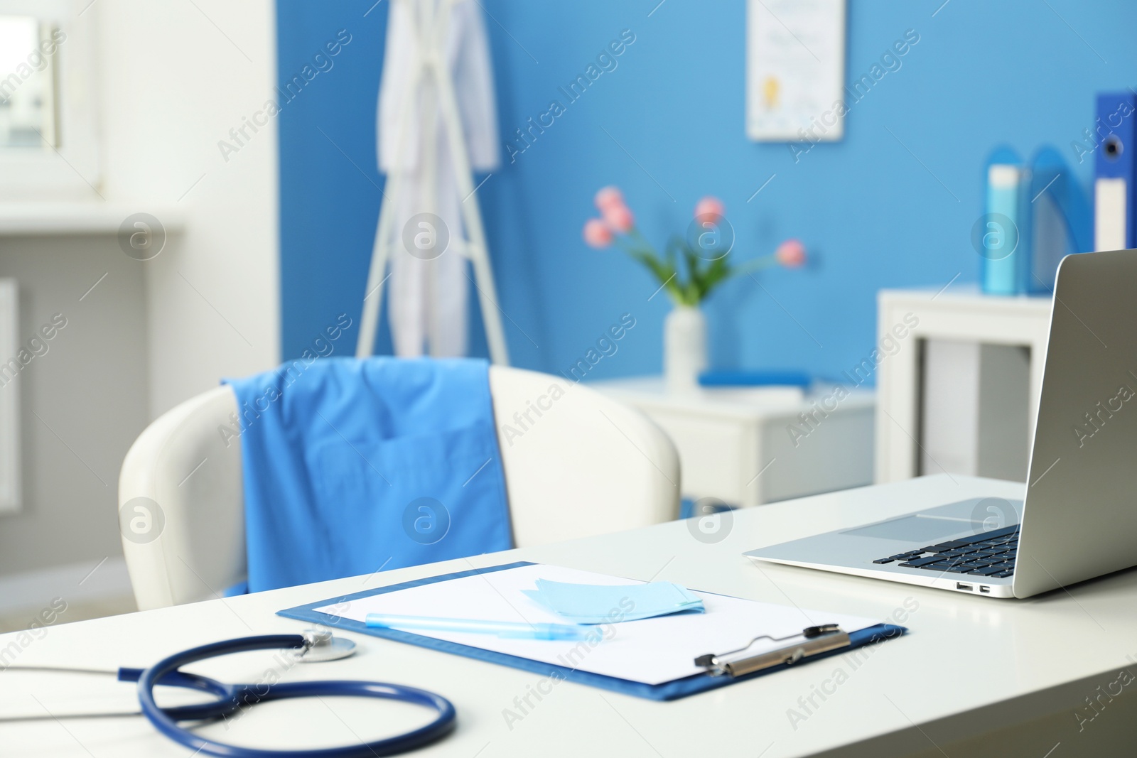 Photo of Doctor's workplace. Clipboard, other stationery, laptop and stethoscope on white table in medical office, closeup