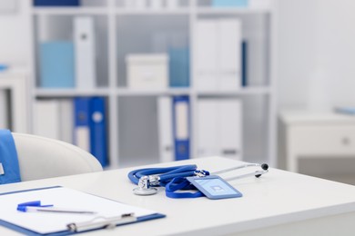 Photo of Doctor's workplace with stethoscope and paperwork on desk, closeup. Space for text