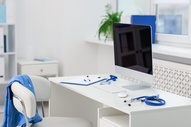 Photo of Doctor's workplace with stethoscope, paperwork and computer on desk
