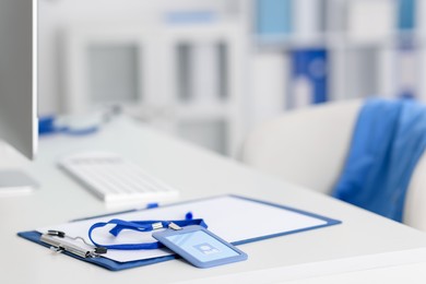 Photo of Clipboard with paperwork and badge on desk in doctor's office, closeup. Space for text