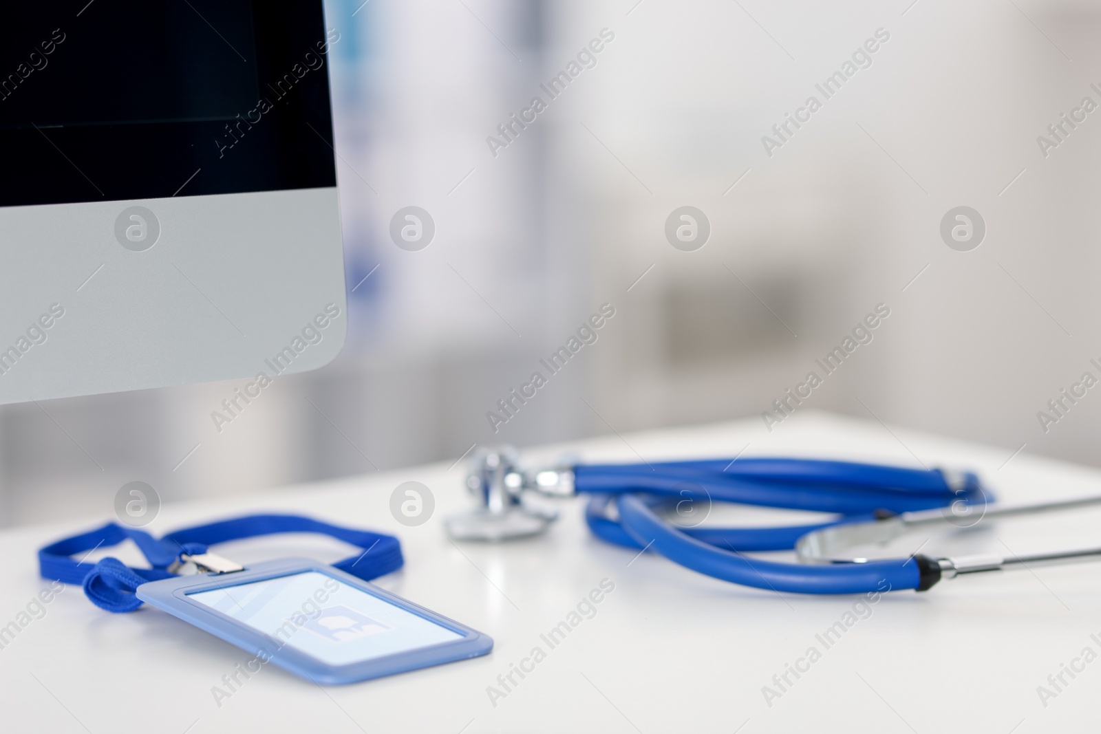Doctor's workplace with stethoscope, badge and computer on desk, closeup. Space for text Photo of Doctor's workplace with stethoscope, badge and computer on desk, closeup. Space for text