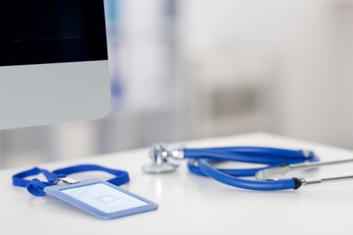 Photo of Doctor's workplace with stethoscope, badge and computer on desk, closeup. Space for text