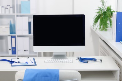Photo of Doctor's workplace with stethoscope, paperwork and computer on desk