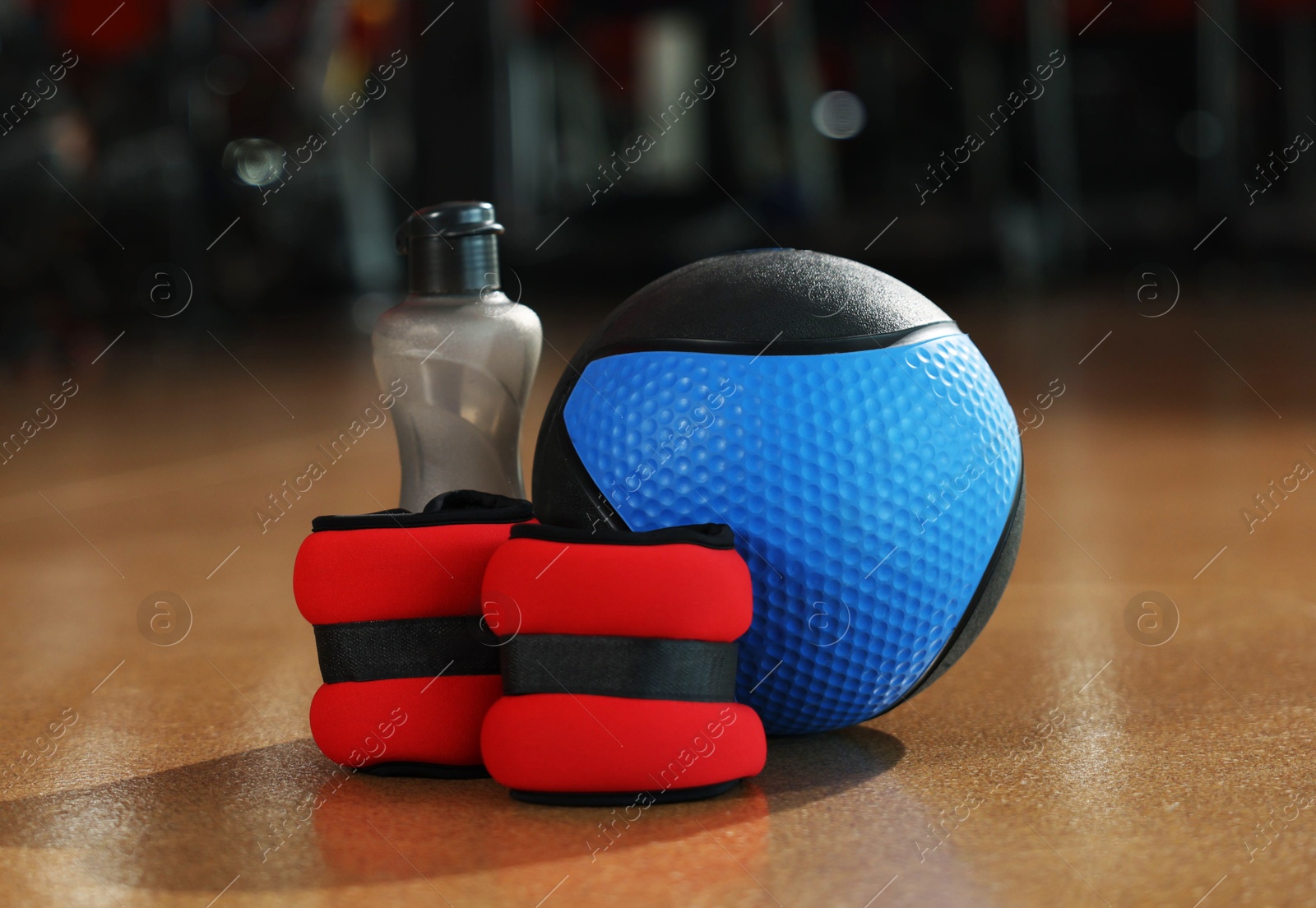 Medicine ball, bottle and ankle weights on floor in gym. Space for text Photo of Medicine ball, bottle and ankle weights on floor in gym. Space for text