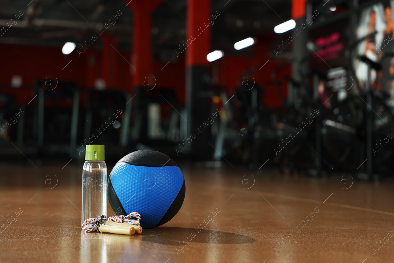 Medicine ball, bottle and skipping rope on floor in gym. Space for text Photo of Medicine ball, bottle and skipping rope on floor in gym. Space for text