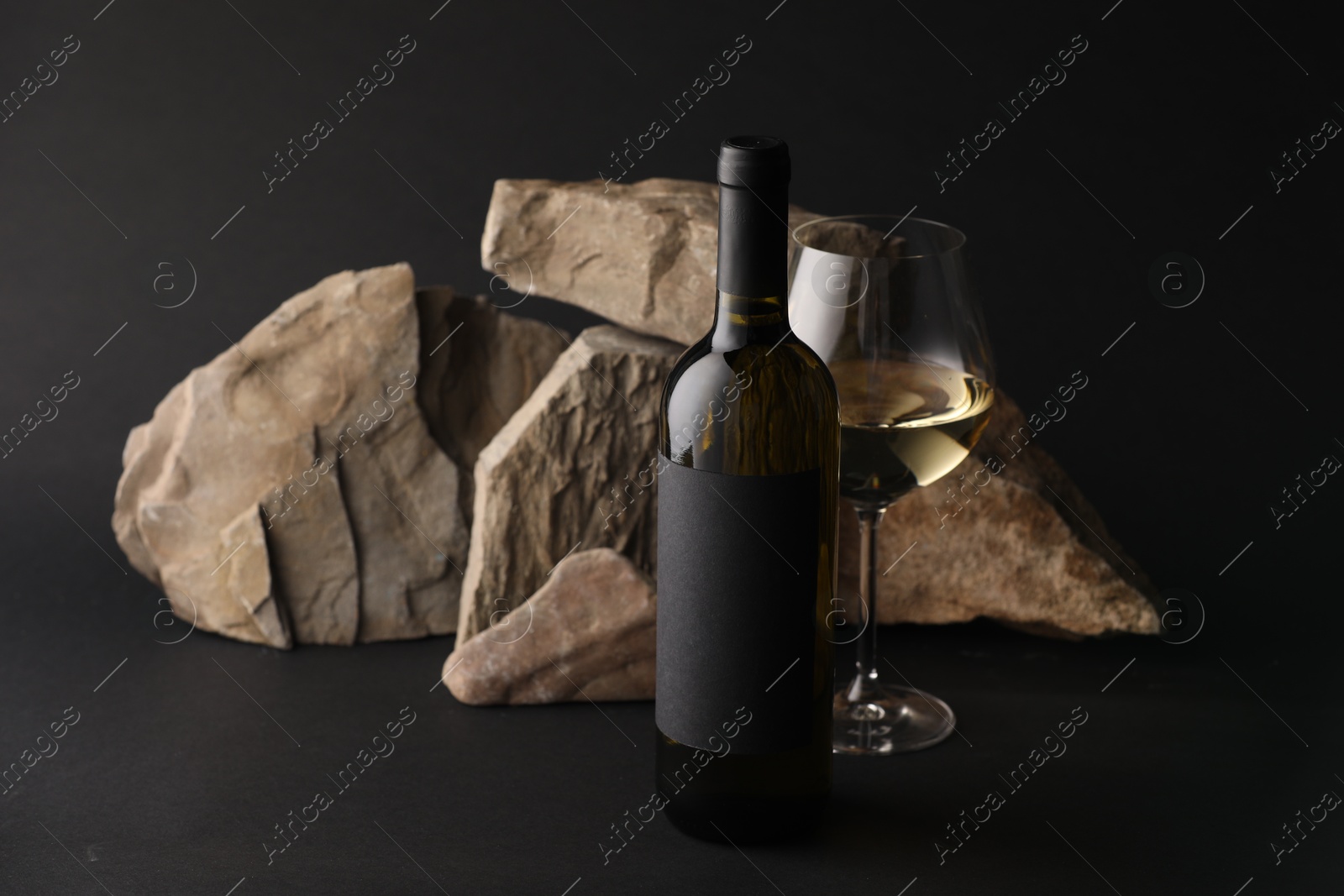 Bottle of wine, wineglass and rocks on black background Photo of Bottle of wine, wineglass and rocks on black background