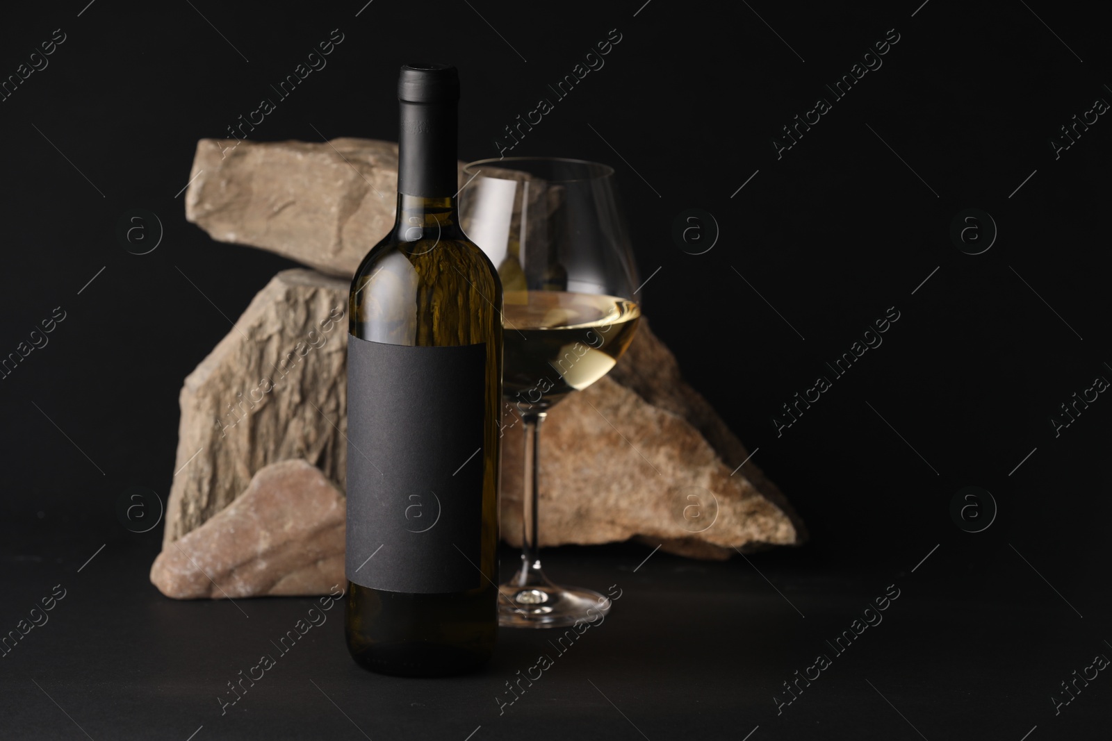 Bottle of wine, wineglass and rocks on black background Photo of Bottle of wine, wineglass and rocks on black background