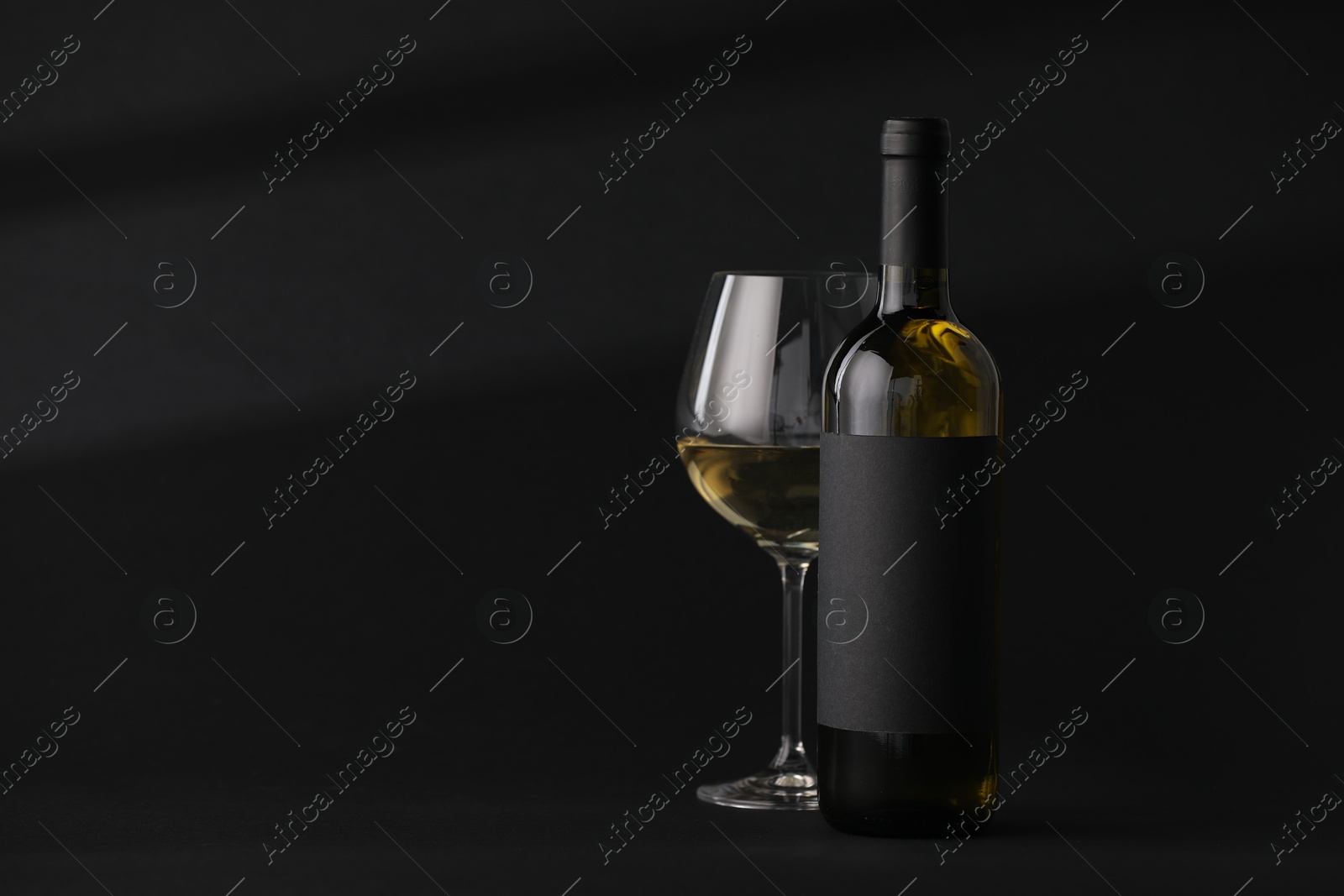 Bottle of wine and wineglass on black background, space for text Photo of Bottle of wine and wineglass on black background, space for text