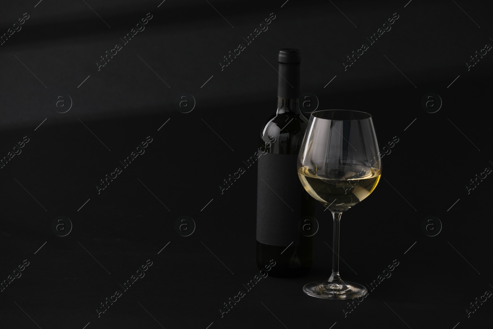 Bottle of wine and wineglass on black background, space for text Photo of Bottle of wine and wineglass on black background, space for text