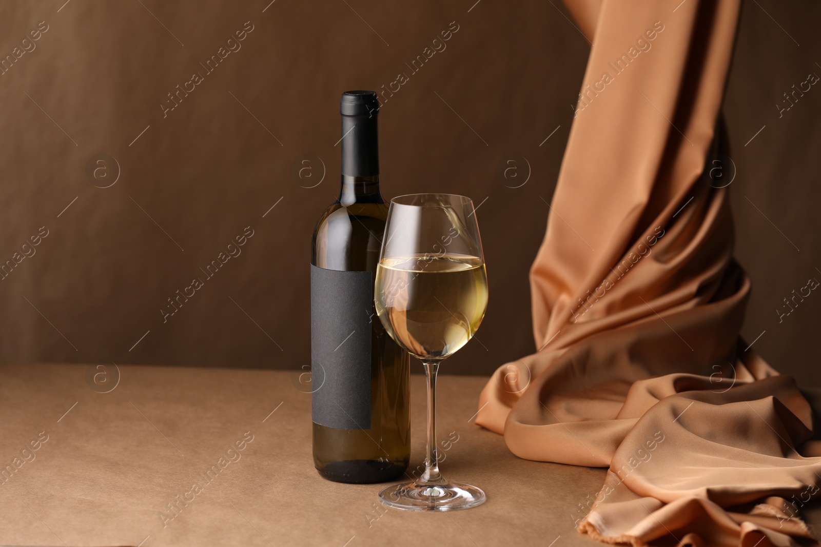 Bottle of wine, wineglass and cloth on brown table, space for text Photo of Bottle of wine, wineglass and cloth on brown table, space for text