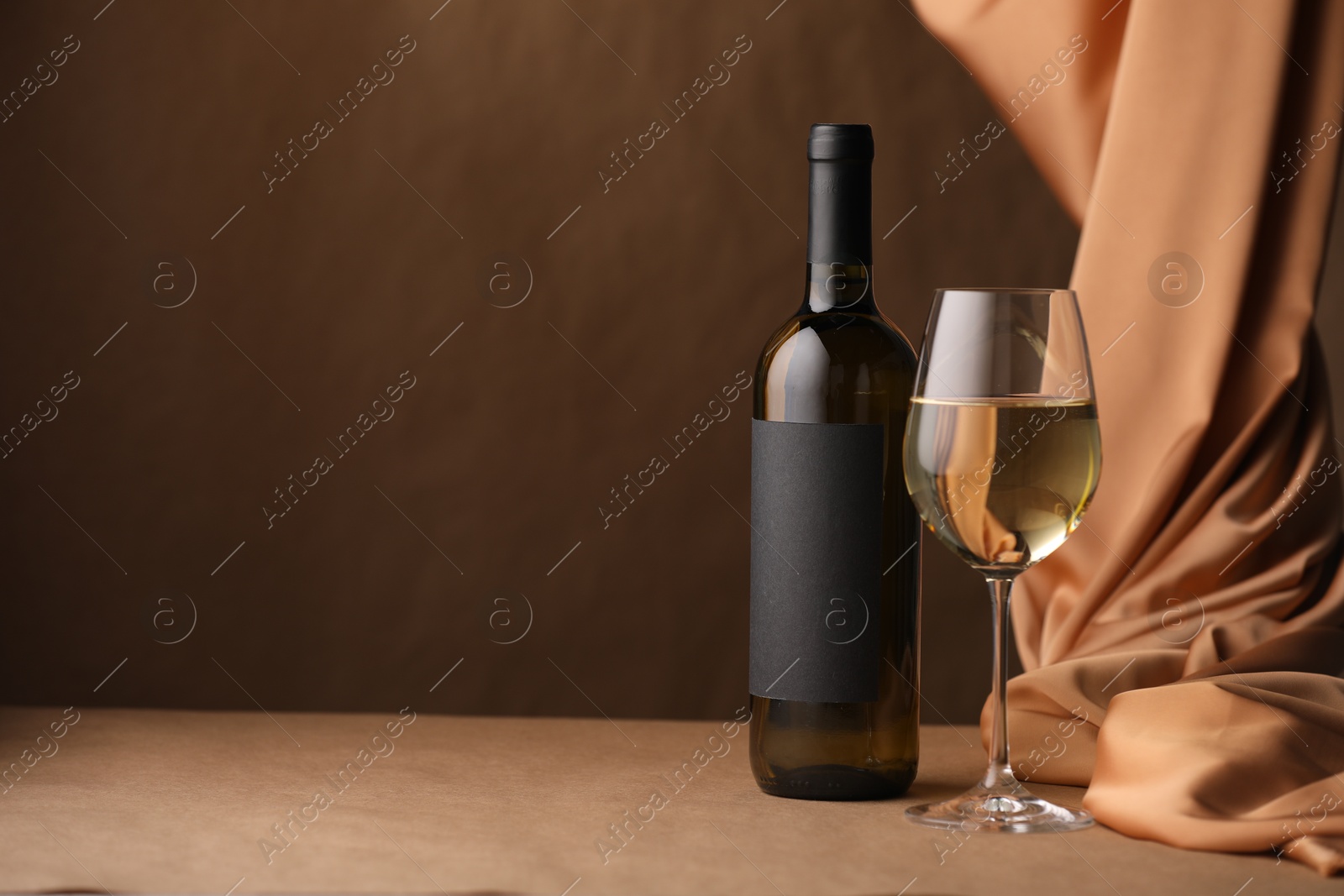 Bottle of wine, wineglass and cloth on brown table, space for text Photo of Bottle of wine, wineglass and cloth on brown table, space for text