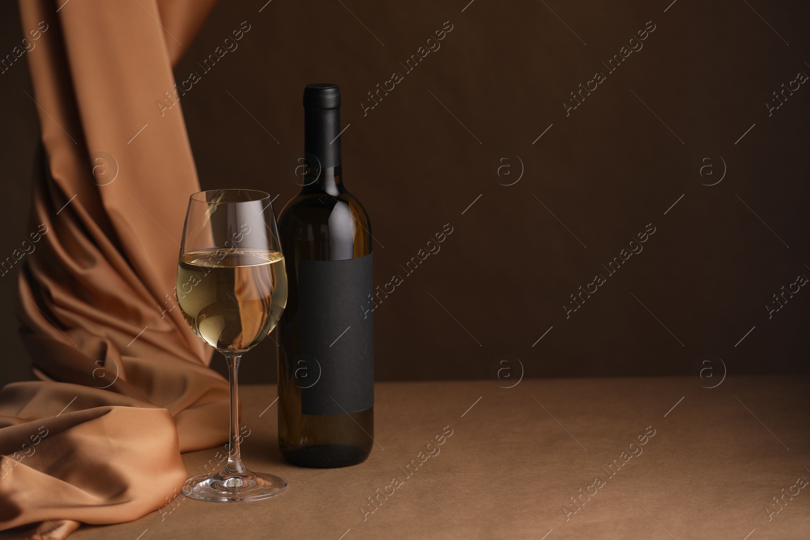 Bottle of wine, wineglass and cloth on brown table, space for text Photo of Bottle of wine, wineglass and cloth on brown table, space for text