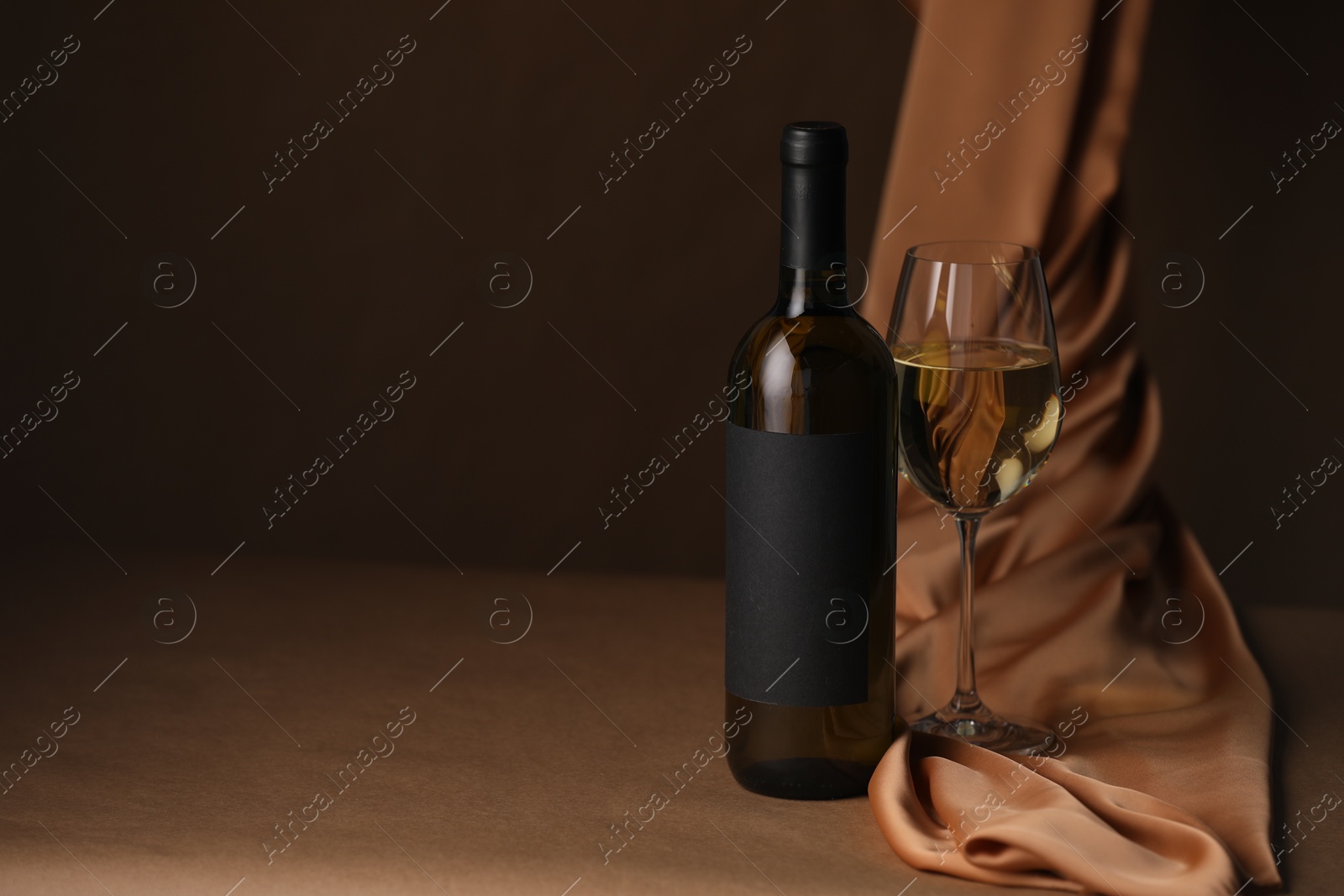 Bottle of wine, wineglass and cloth on brown table, space for text Photo of Bottle of wine, wineglass and cloth on brown table, space for text
