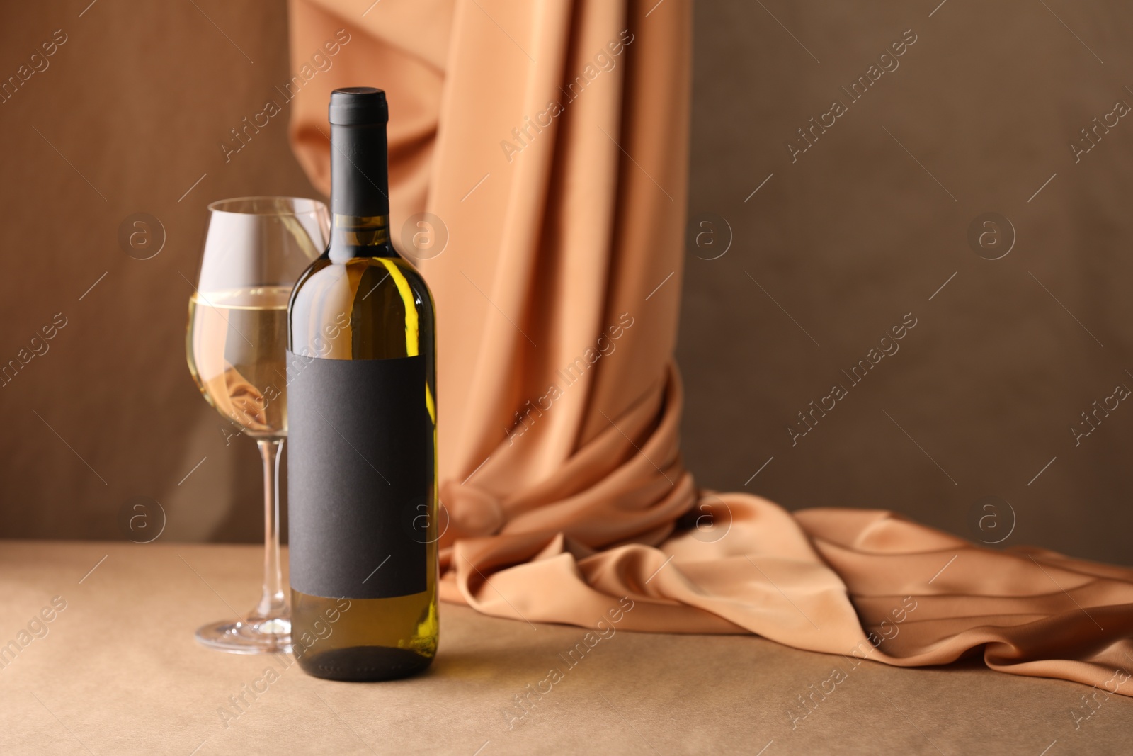 Bottle of wine, wineglass and cloth on brown table, space for text Photo of Bottle of wine, wineglass and cloth on brown table, space for text