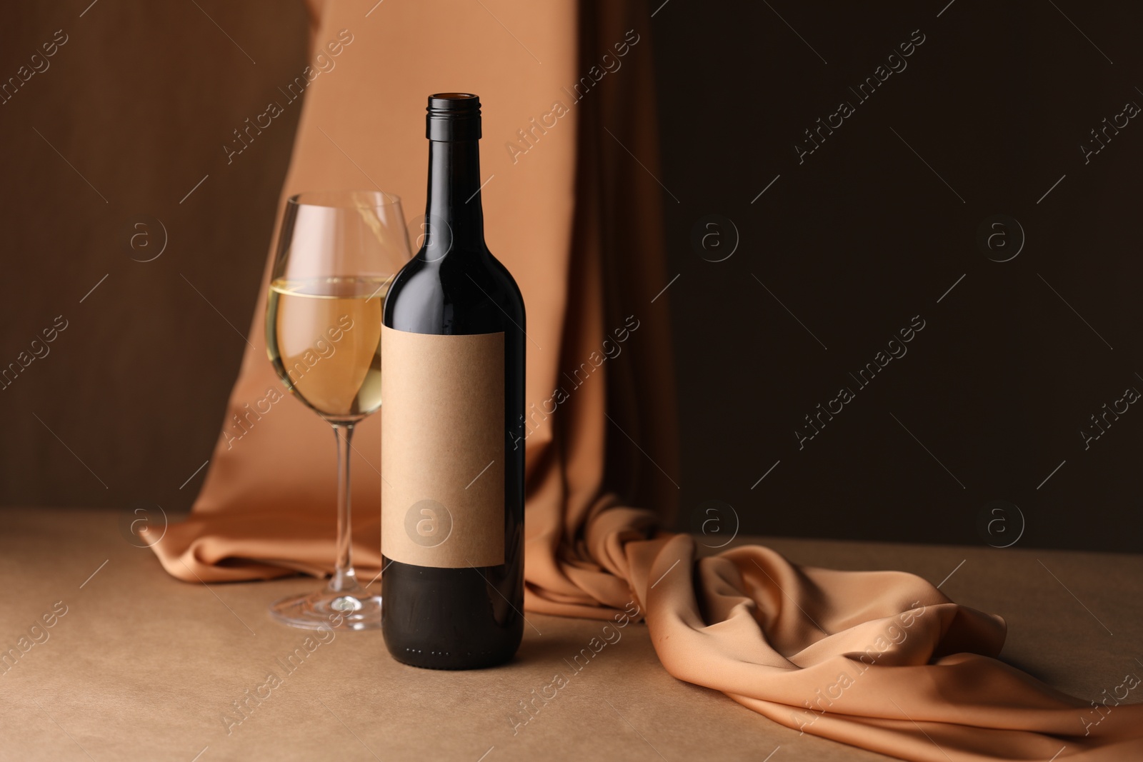 Bottle of wine, wineglass and cloth on brown table, space for text Photo of Bottle of wine, wineglass and cloth on brown table, space for text