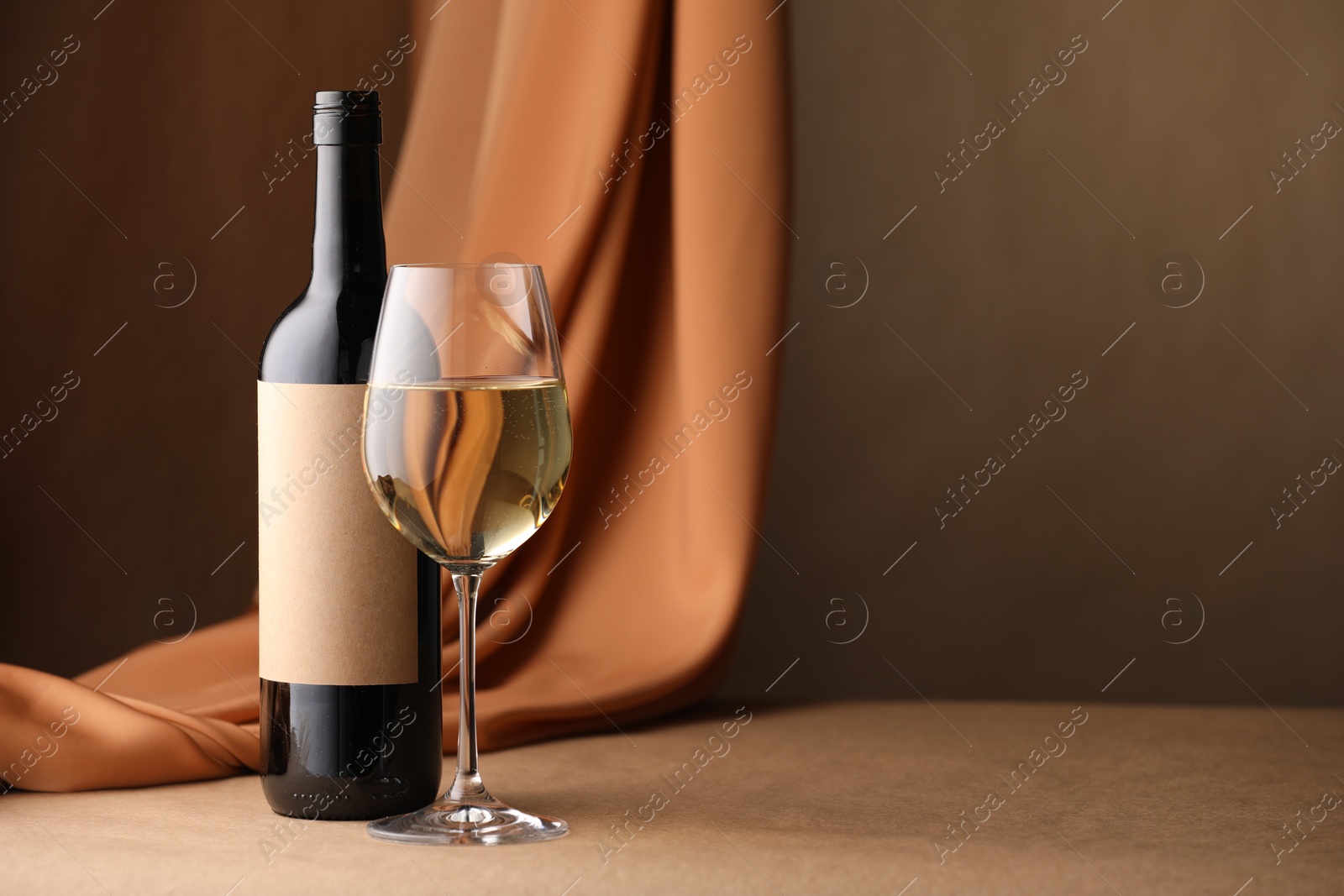 Bottle of wine, wineglass and cloth on brown table, space for text Photo of Bottle of wine, wineglass and cloth on brown table, space for text