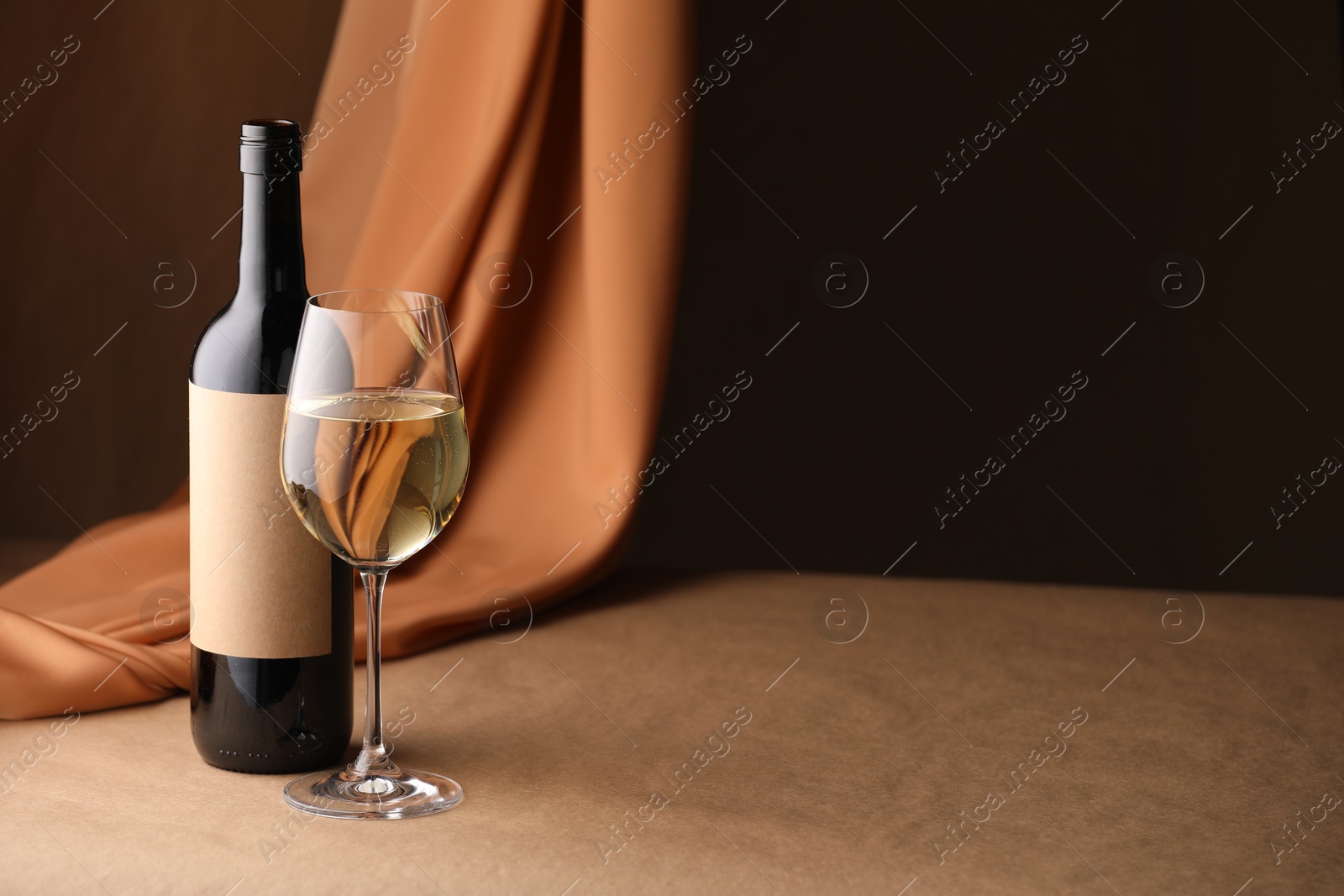 Bottle of wine, wineglass and cloth on brown table, space for text Photo of Bottle of wine, wineglass and cloth on brown table, space for text