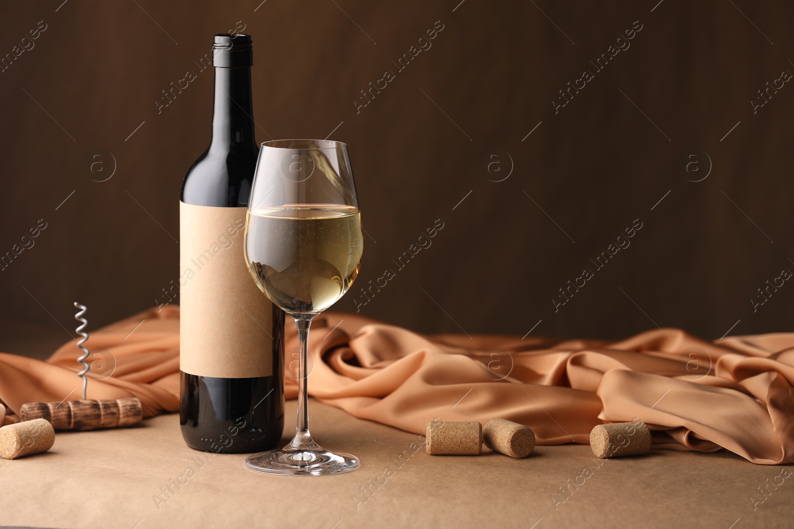 Bottle of wine, wineglass and cloth on brown table, space for text Photo of Bottle of wine, wineglass and cloth on brown table, space for text