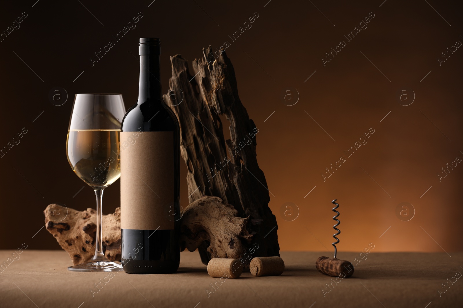 Bottle of wine, tree bark, corkscrew and wineglass on brown table against dark background, space for text Photo of Bottle of wine, tree bark, corkscrew and wineglass on brown table against dark background, space for text