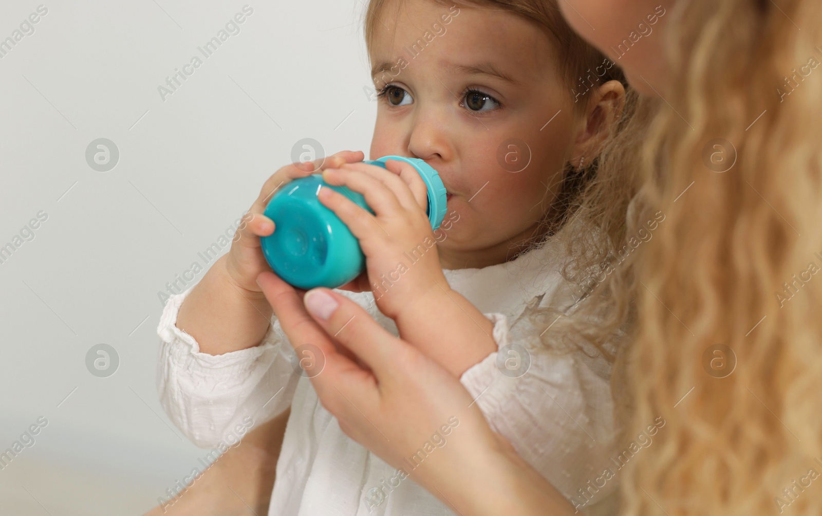 Mother feeding her little baby from bottle at home, closeup Photo of Mother feeding her little baby from bottle at home, closeup