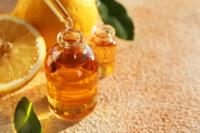 Photo of Taking aromatic oil from perfume bottle with dropper on beige textured background, closeup. Space for text