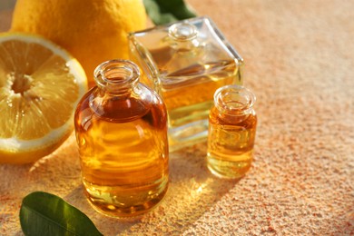 Photo of Perfume bottles with aromatic oils and lemons on beige textured background, closeup
