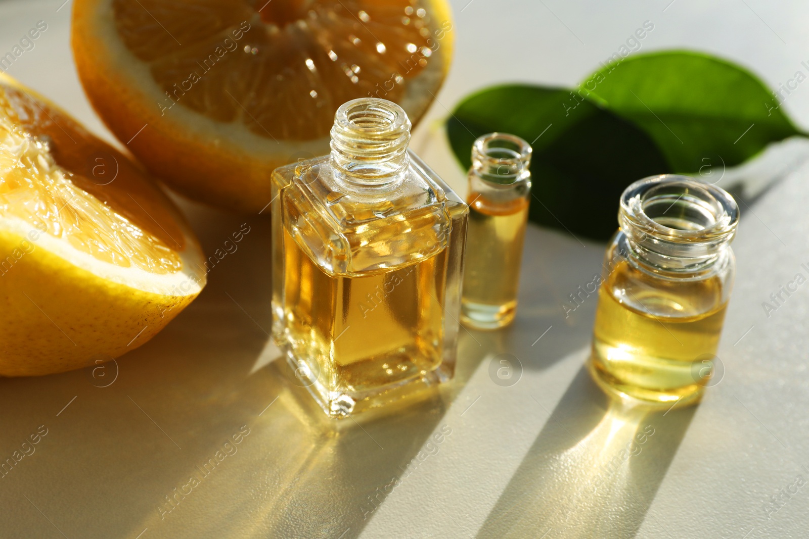 Photo of Perfume bottles with aromatic oils and lemons on light background, closeup