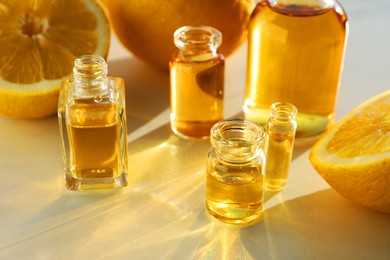 Photo of Perfume bottles with aromatic oils and lemons on light background, closeup