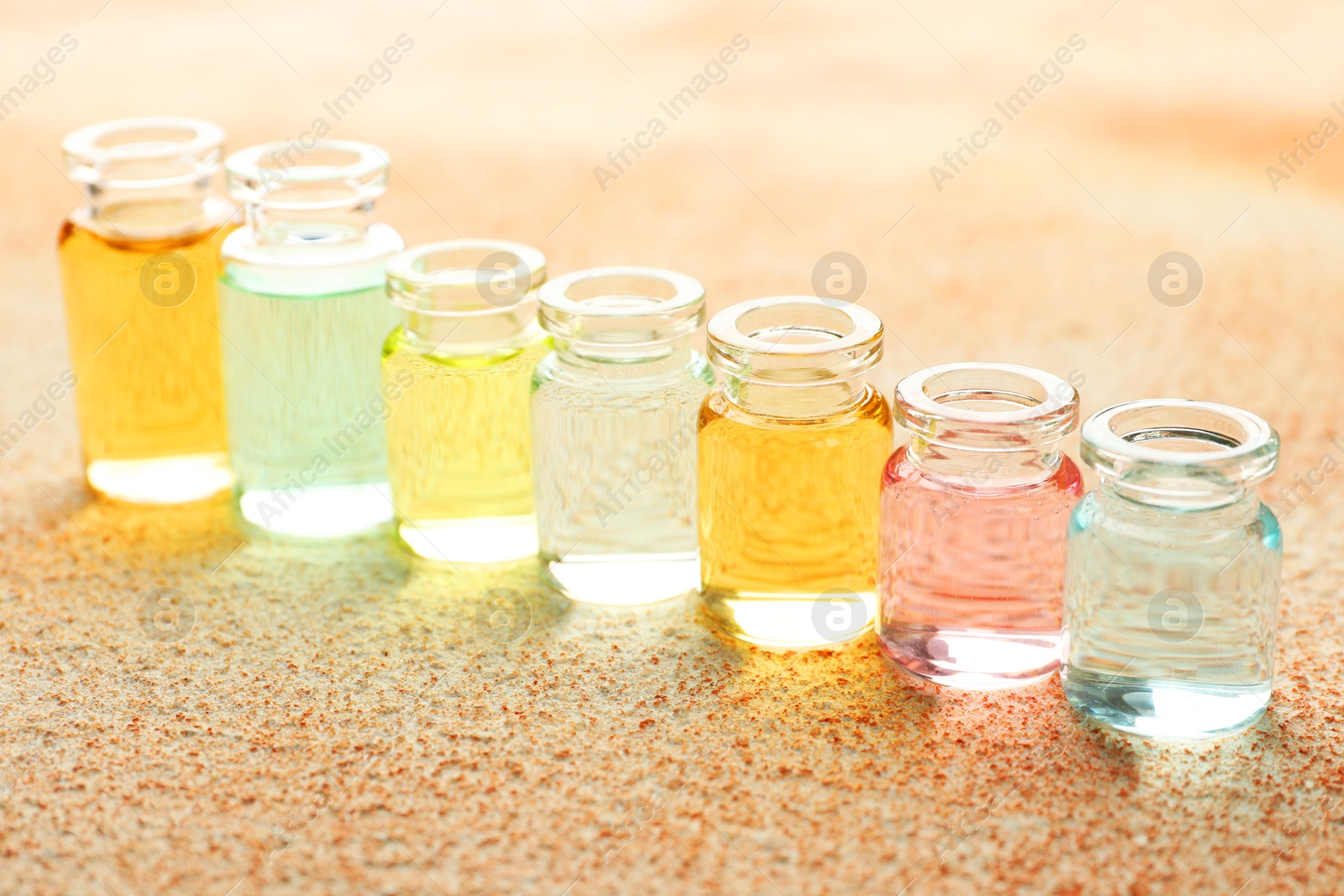 Photo of Perfume bottles with aromatic oils on beige textured background, closeup