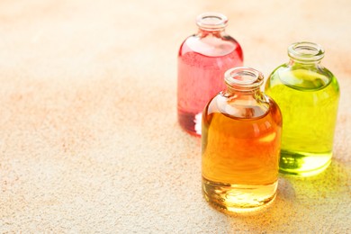 Photo of Perfume bottles with aromatic oils on beige textured background, closeup. Space for text