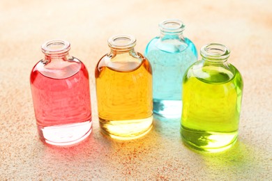 Photo of Perfume bottles with aromatic oils on beige textured background, closeup