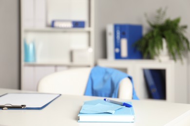 Photo of Doctor's workplace. Clipboard and other stationery on white table in medical office, closeup