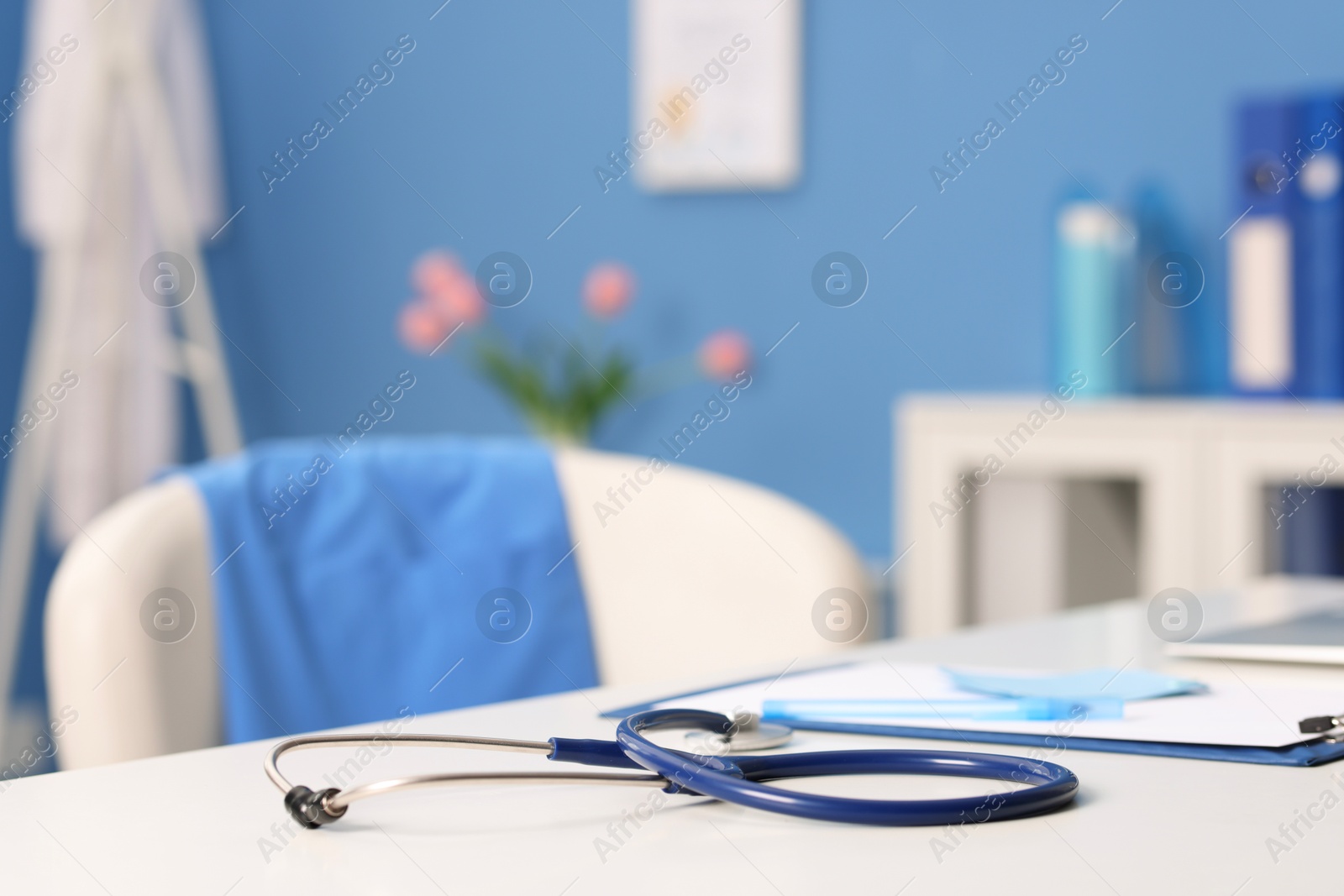 Doctor's workplace. Stethoscope, clipboard and pen on white table in medical office, closeup Photo of Doctor's workplace. Stethoscope, clipboard and pen on white table in medical office, closeup
